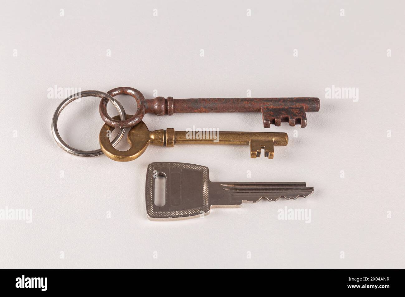 Zwei alte und ein neuer Schlüssel auf weißer Oberfläche. Stockfoto