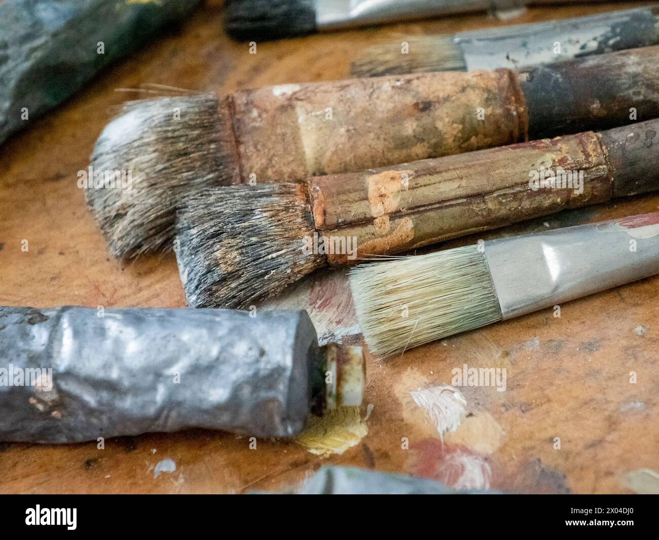 Benutzte Künstlerpinsel, Röhre und Palette von farbenfroher Ölfarbe auf hölzernem Hintergrund, zum Zeichnen und Malen Stockfoto