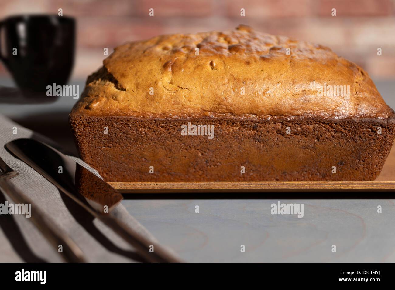Bananenbrot, gebacken zu einer goldenen Kruste und auf ein Holzblech gelegt Stockfoto