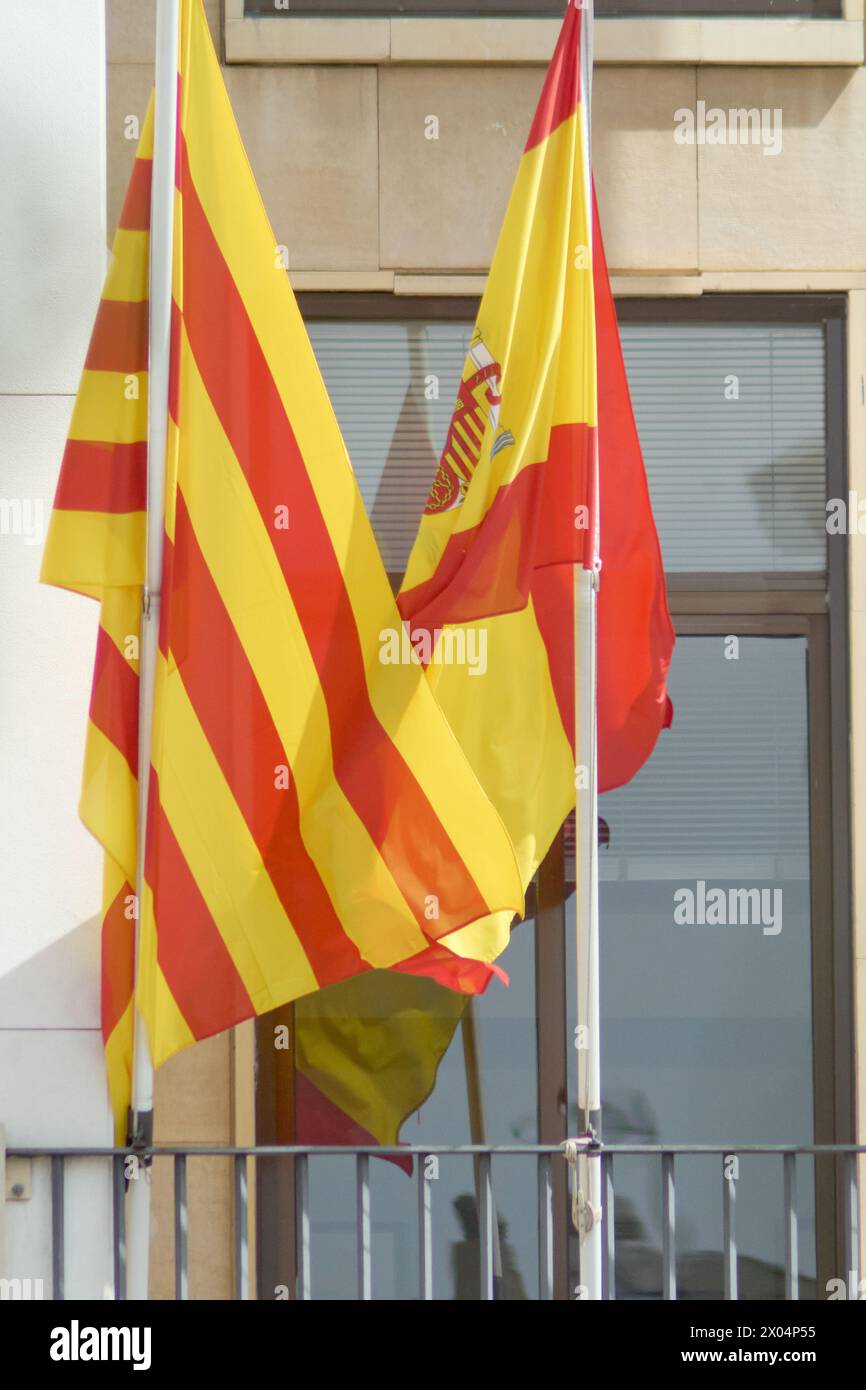 Lebhafte spanische und katalanische Fahnen flattern zusammen, ihre Farben zeugen von der reichen kulturellen Wandteppiche und der gemeinsamen Geschichte. Stockfoto