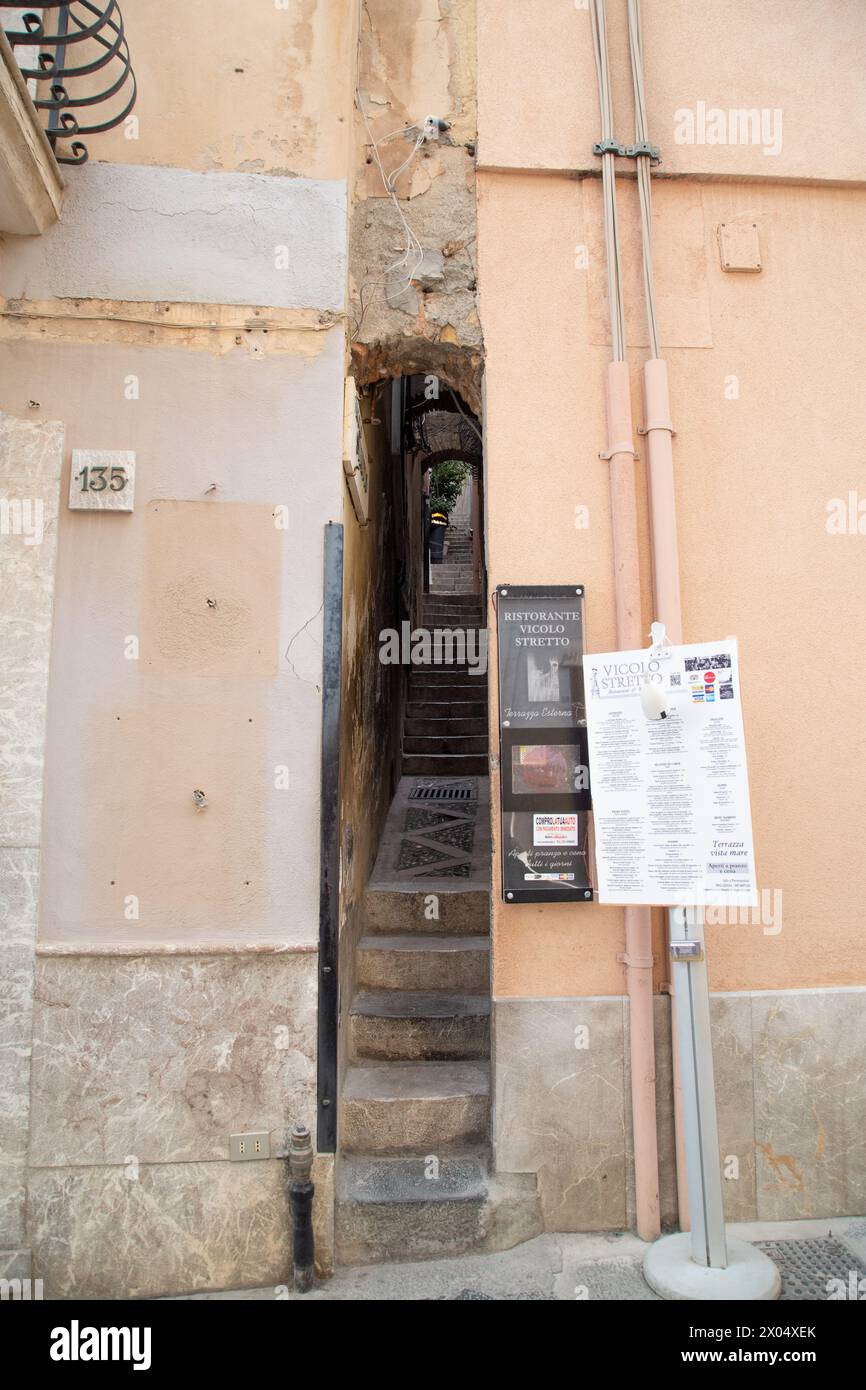 Kaum breit genug, um sich durchzuquetschen, führt diese winzige Straße hinauf zu einem Restaurant in der Stadt Taormina Stockfoto