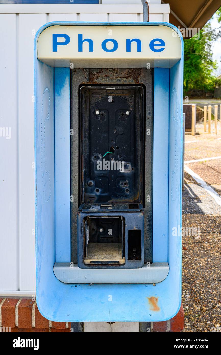 Alte kaputte Telefonkabine oder Telefonständer mit beschädigtem Telefon, das urbanes Feuer und veraltete Technologie in Montgomery Alabama, USA, zeigt. Stockfoto