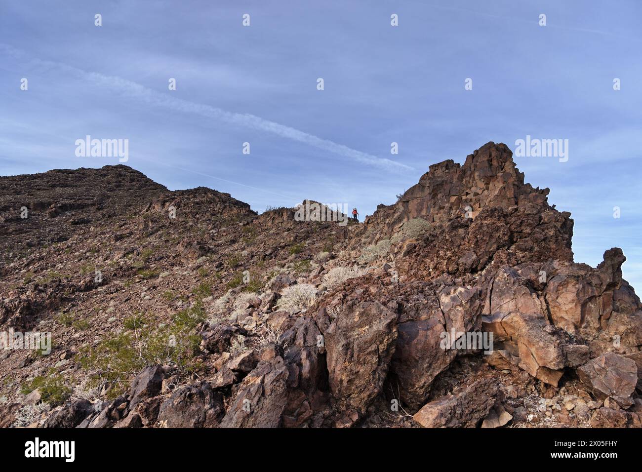 Eine ferne Frau, die einen Bergrücken vom Wüstengrat des Negro Peak in den Turtle Mountains im Osten Kaliforniens absteigt Stockfoto