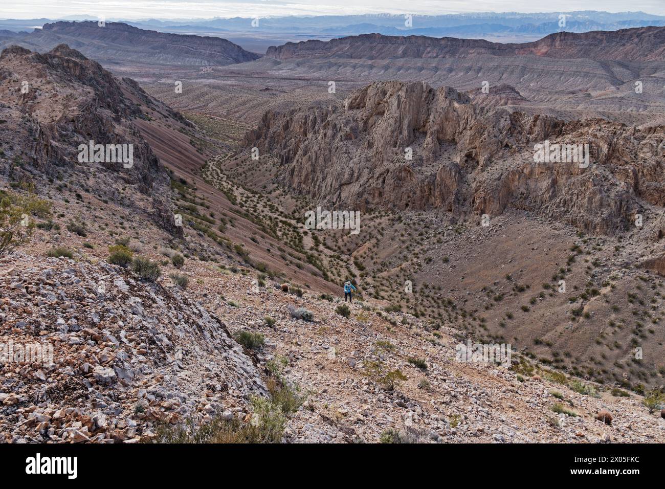 Eine ferne Frau in Blau wandert auf Talus und Geröll auf der Weiser Ridge in den North Muddy Mountains der Nevada-Wüste Stockfoto