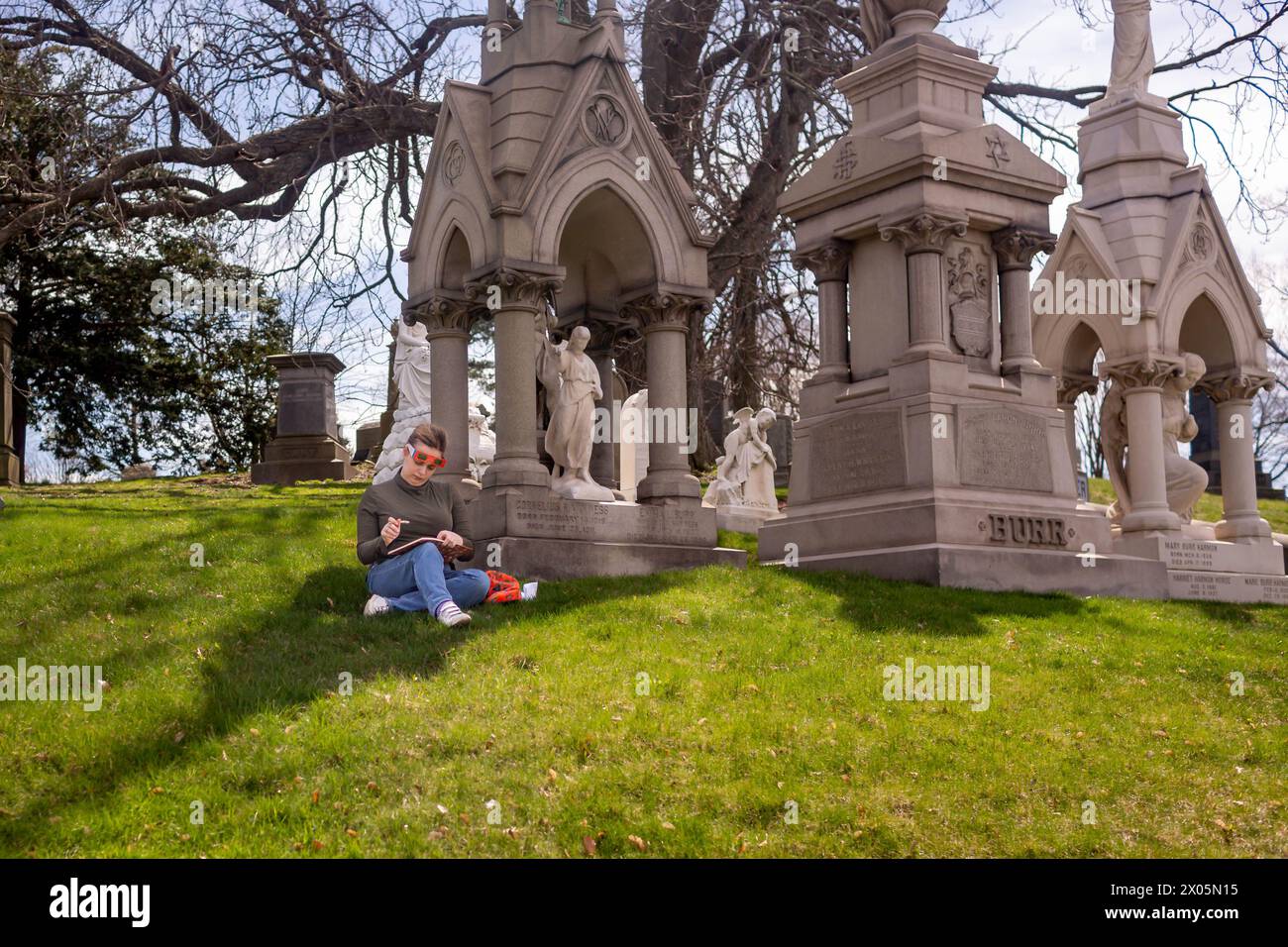 Brooklyn, Usa. April 2024. Die Leute versammeln sich auf dem Greenwood Cemetery in Brooklyn, um eine partielle Sonnenfinsternis zu erleben. Tausende versammelten sich in Parks und offenen Plätzen in der Stadt, um bis zu 90 % der Sonne zu sehen, die vom Mond bedeckt ist. (Foto: Michael Nigro/Pacific Press) Credit: Pacific Press Media Production Corp./Alamy Live News Stockfoto