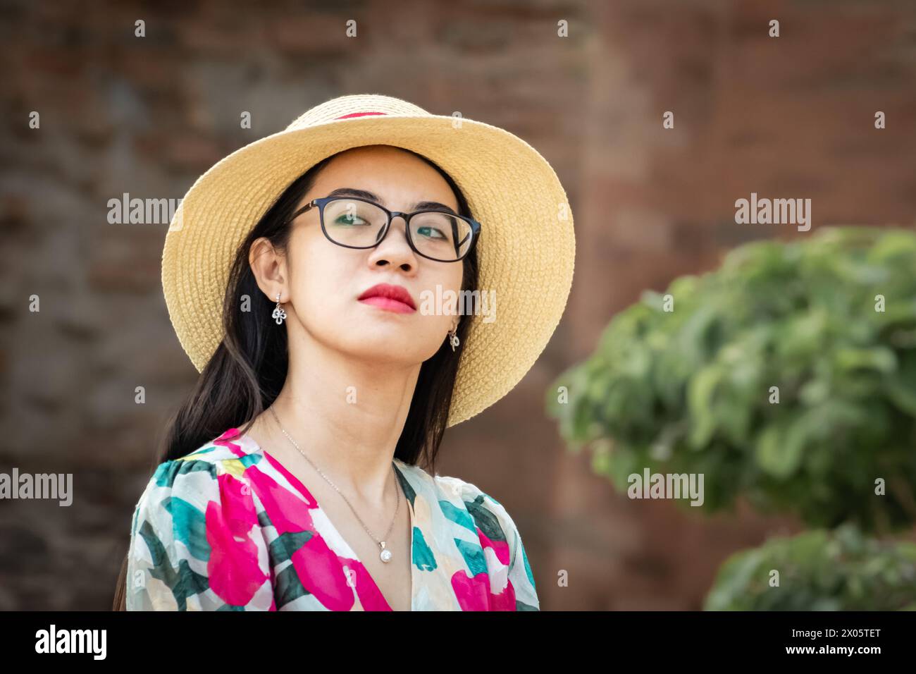 Junge elegante, schöne asiatische Frau in Sommerkleidung und mit Strohhut. Asiatische Frau genießt Urlaub. Frau im Sonnenhut auf Vacati Stockfoto