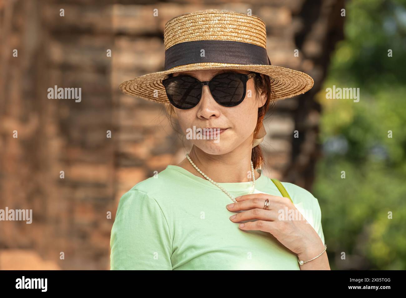 Junge elegante, schöne asiatische Frau in Sommerkleidung und mit Strohhut. Asiatische Frau genießt Urlaub. Frau im Sonnenhut auf Vacati Stockfoto