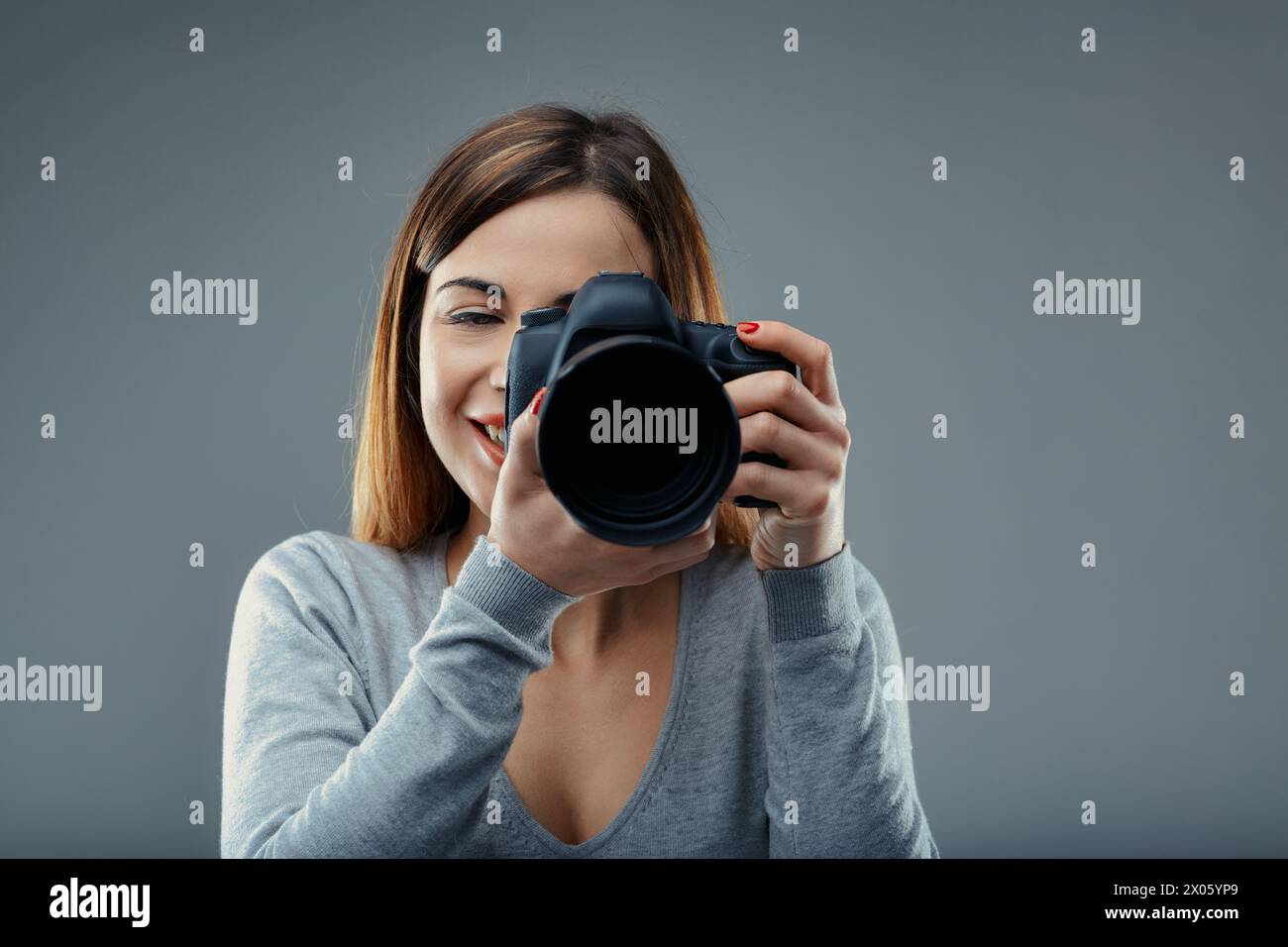 Die konzentrierten Augen der Frau harmonieren mit ihrer Kamera und warten auf den entscheidenden Moment Stockfoto