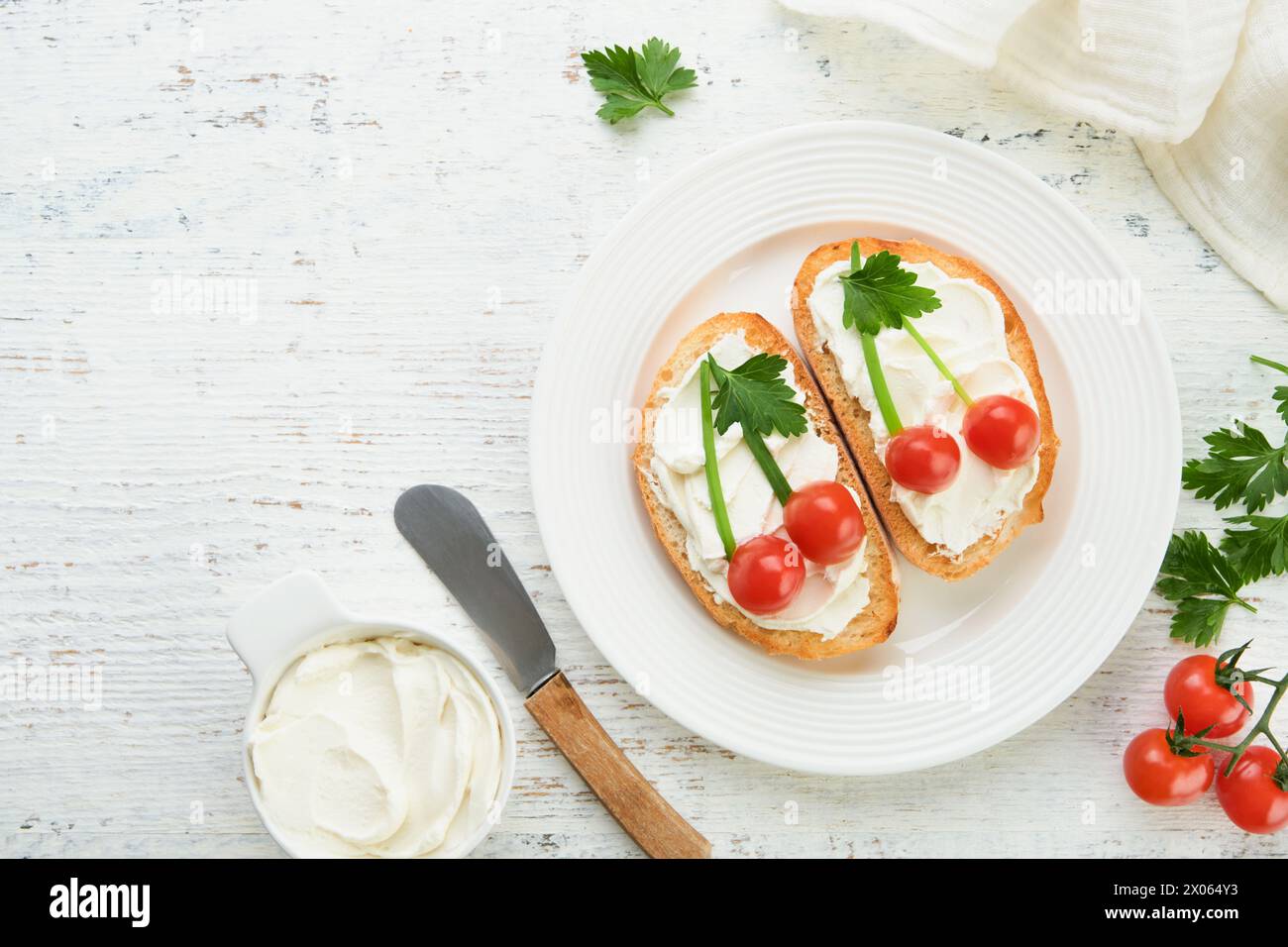 Lustiger Toast in Form eines Reifen Kirschen-Sandwiches mit Frischkäse, Brot, Kirschtomaten, Zwiebeln und Petersilie. Food Art Idee für Kinderessen. Kreative Pause Stockfoto