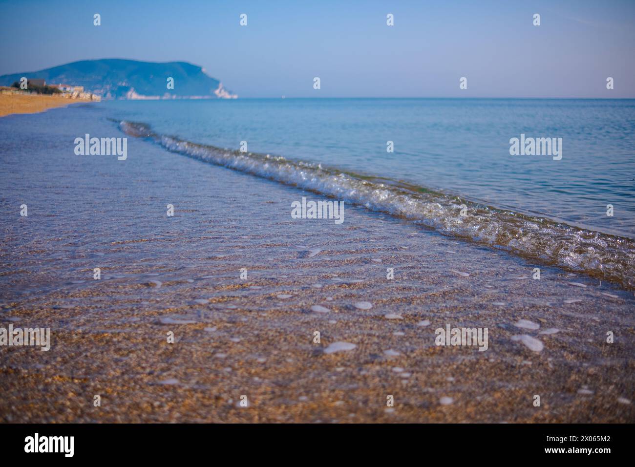 Wunderschönes ruhiges Meer an einem sonnigen Tag. Meereslicht-Surf-Aufnahme aus nächster Nähe. Eine kleine Welle und ein Meeresschaum glitzern in der Sonne. Stockfoto