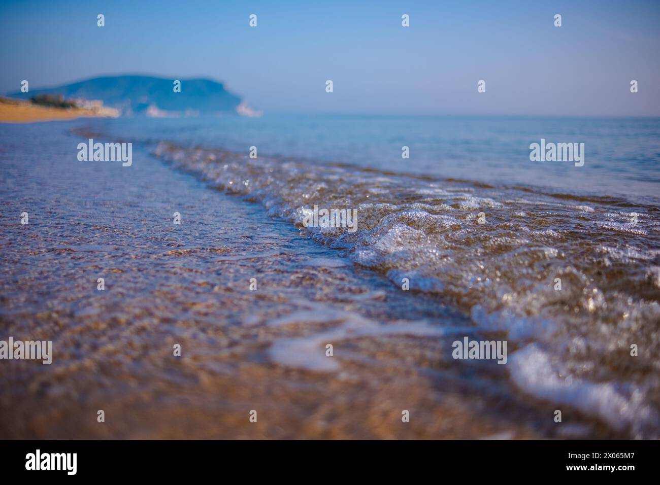 Wunderschönes ruhiges Meer an einem sonnigen Tag. Meereslicht-Surf-Aufnahme aus nächster Nähe. Eine kleine Welle und ein Meeresschaum glitzern in der Sonne. Stockfoto
