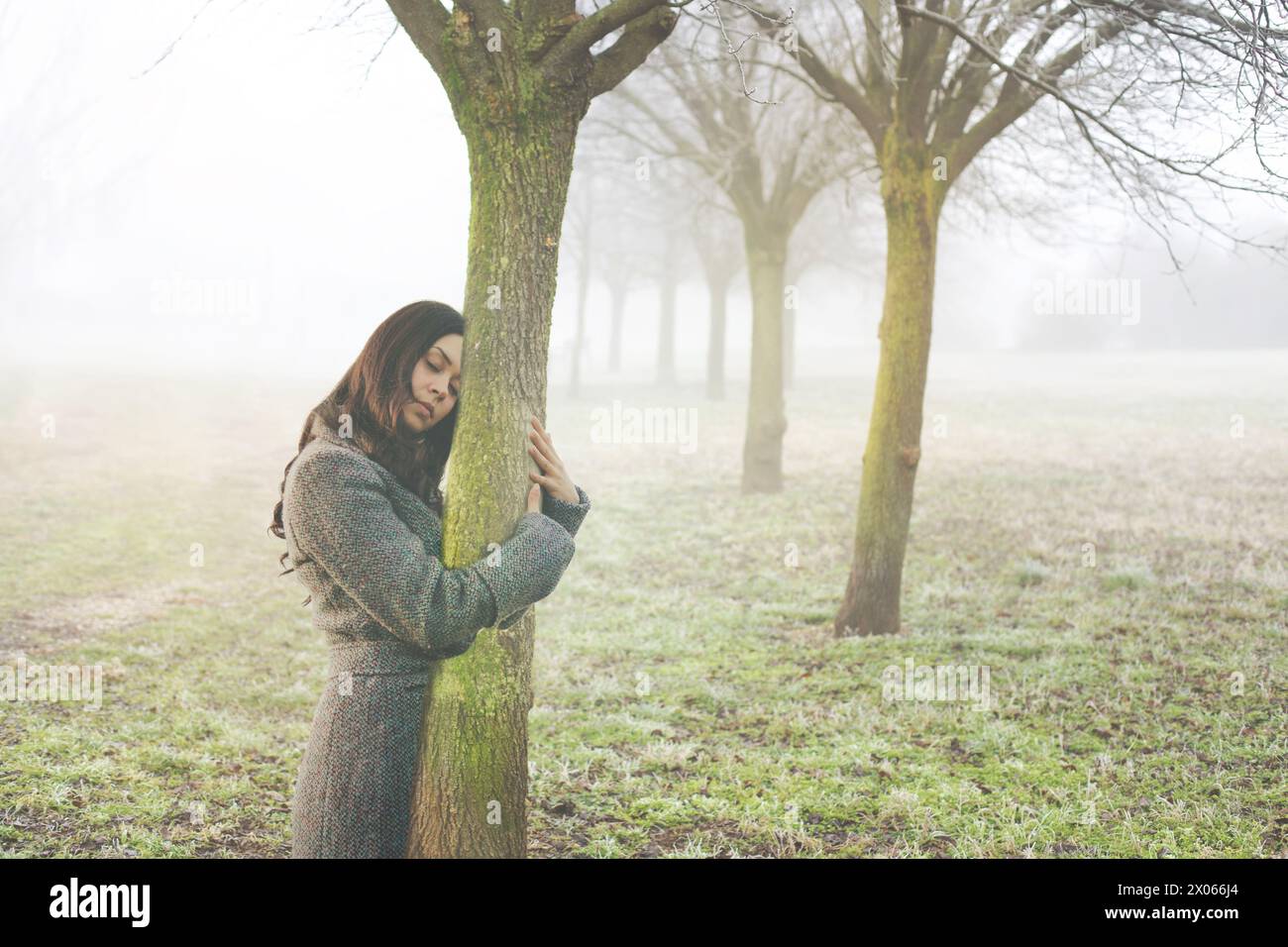 Frau umarmt sanft den Stamm eines Baumes, der das abstrakte Konzept des Lebensbluts symbolisiert Stockfoto