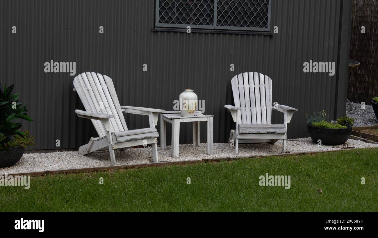 Zwei Adirondack-Stühle mit Tisch und Blick auf den Hinterhof Stockfoto