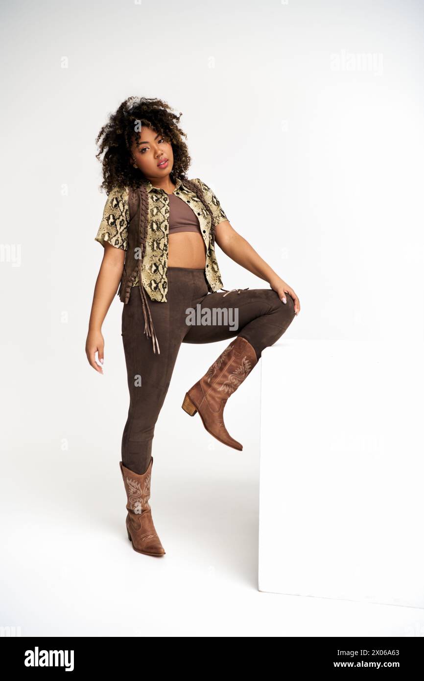 Elegante afroamerikanische Frau mit Animalprint auf der Kleidung neben dem Würfel, die in die Kamera schaut Stockfoto