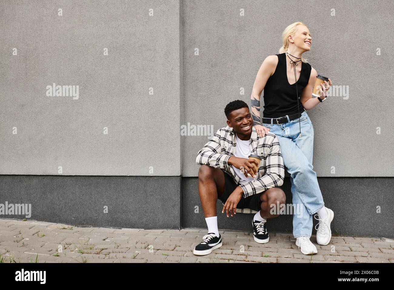 Ein multikulturelles Paar sitzt friedlich nebeneinander auf dem städtischen Bürgersteig und teilt einen zarten Moment der Zweisamkeit. Stockfoto