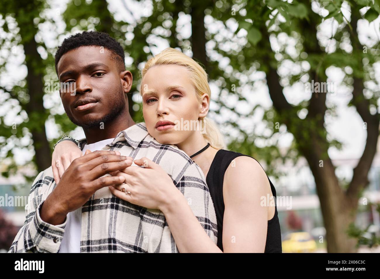 Ein glückliches multikulturelles Paar, ein Afroamerikaner und eine Kaukasierin, die einen zärtlichen Moment draußen in einem Park teilen. Stockfoto