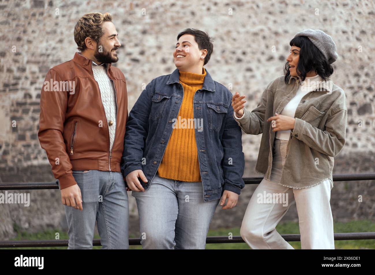 Drei trendige Freunde, darunter ein geschlechtsorientiertes Individuum, lachen in einer urbanen Umgebung – Diversität und Inklusivität Stockfoto