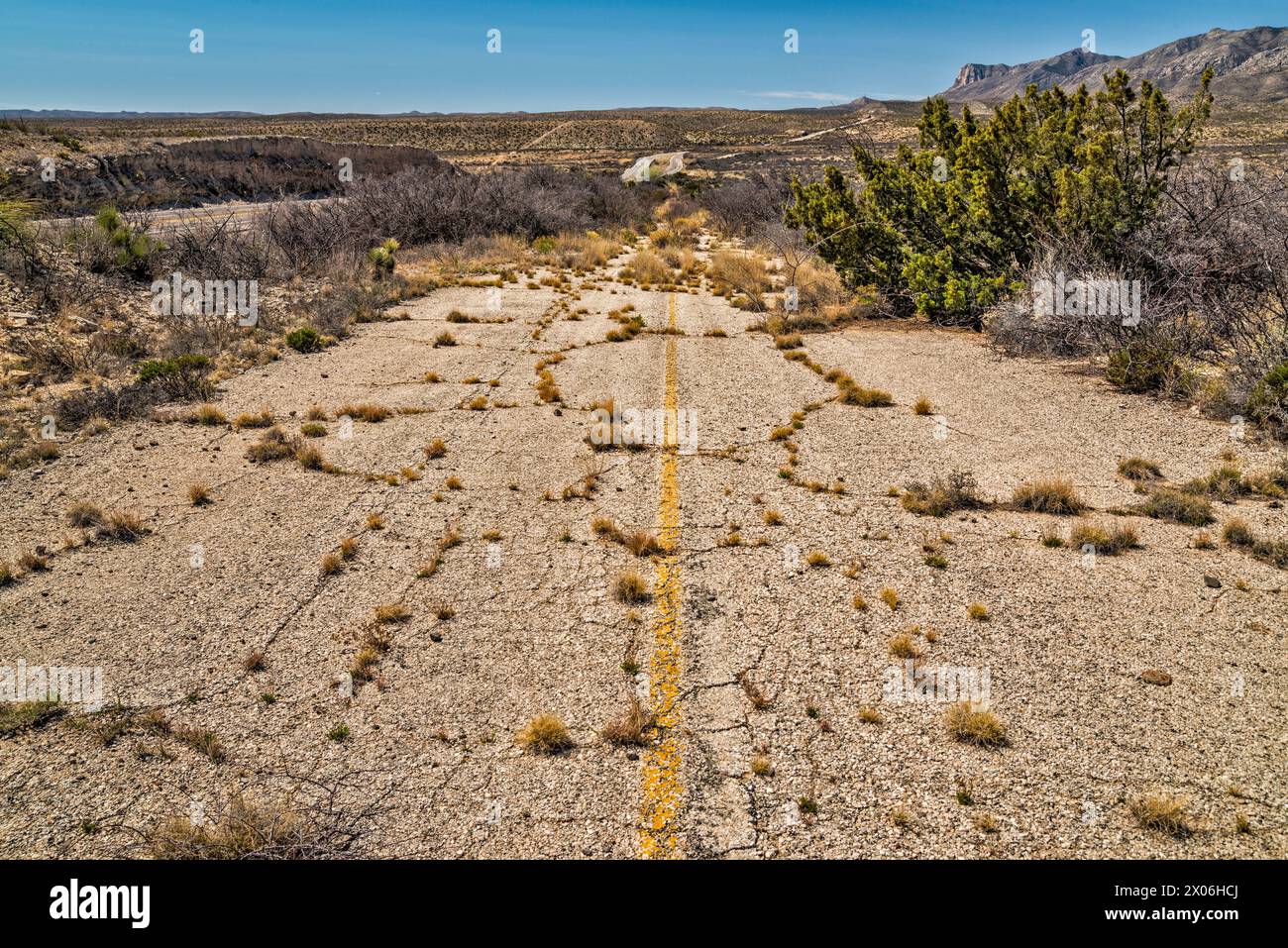 Verlassener Abschnitt der US-180, US-62 Highway mit Überwuchs, Guadalupe Mountains in der Ferne, Texas, USA Stockfoto