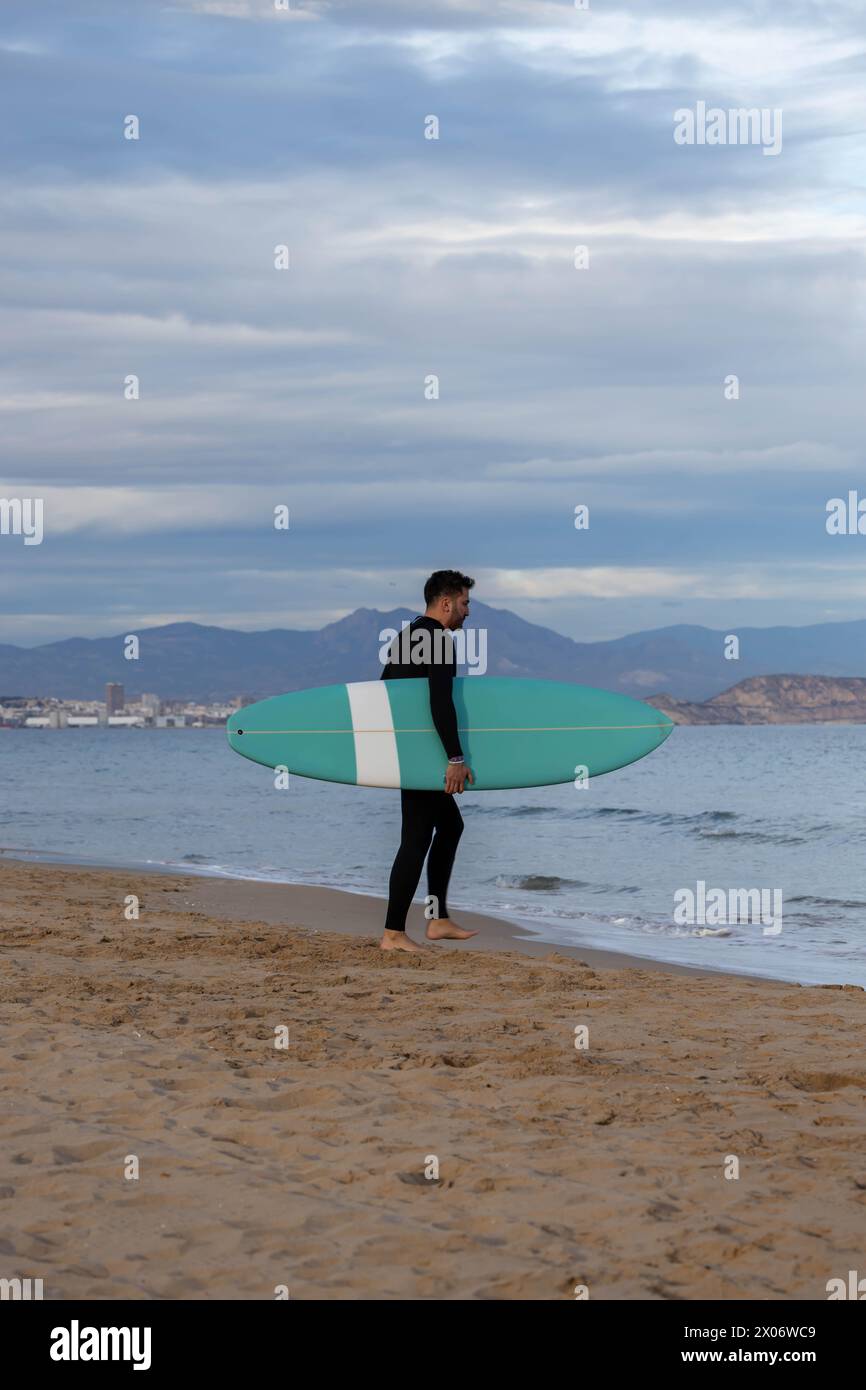Surfer mit Neoprenanzug und Surfbrett am Strand Stockfoto