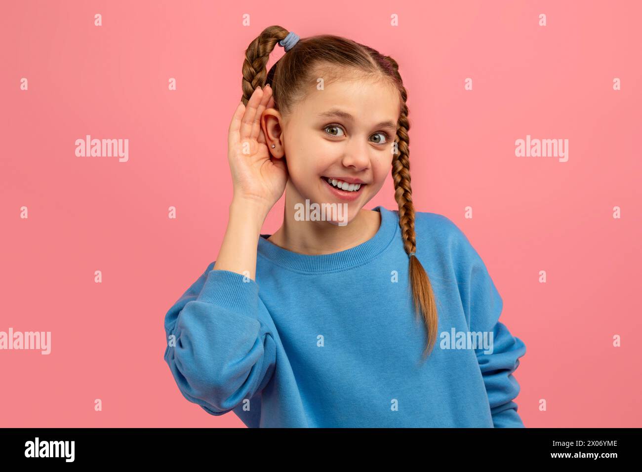 Ein Mädchen, das mit Hand-Ohr auf Rosa zuhört Stockfoto