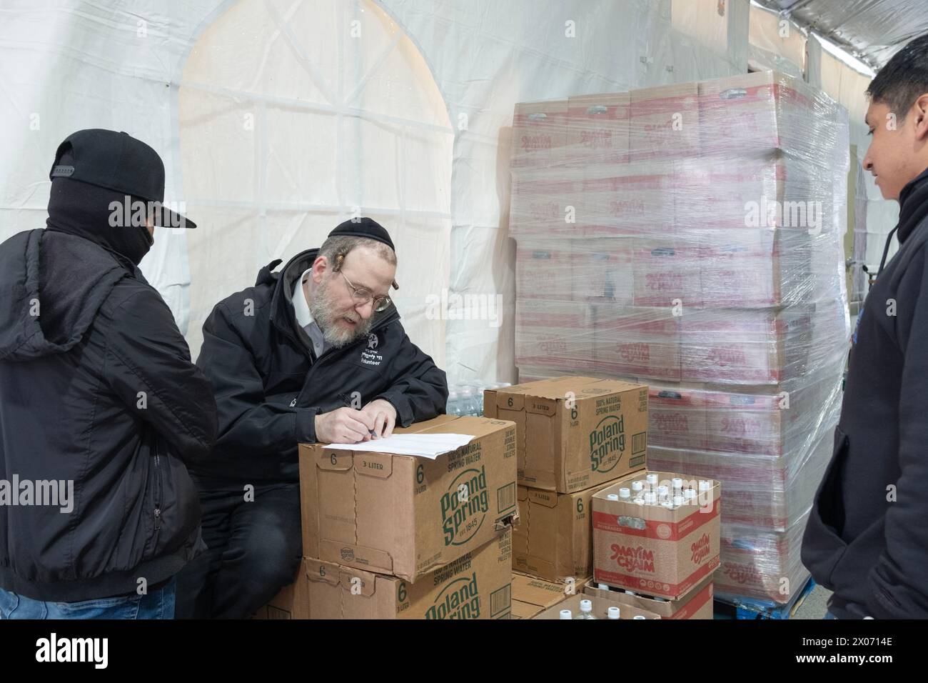 Ein orthodoxer jüdischer Manager in einem koscheren Supermarkt unterweist zwei junge hispanische Männer in sein Personal. In Brooklyn, New York Stockfoto