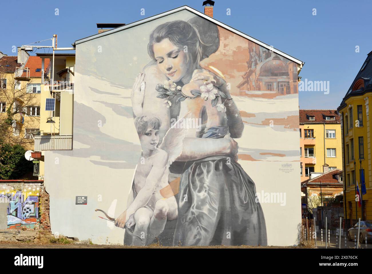 Wandgemälde die Umarmung, die ein Paar umarmt und einen kleinen Jungen als Eros der Gott der Liebe in Sofia Bulgarien, Osteuropa, Balkan, EU darstellt Stockfoto