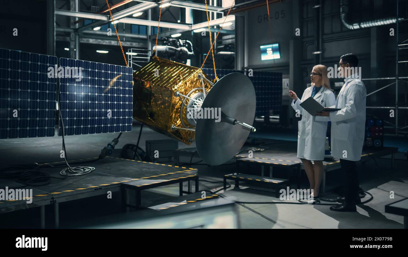 Ingenieur und Techniker, die an der Satellitenkonstruktion arbeiten. Luft- und Raumfahrtbehörde: Ein Team von Wissenschaftlern, das technologische Ausrüstung und Tablet-Computer zur Entwicklung von Raumfahrzeugen für die Weltraumforschung nutzt. Stockfoto