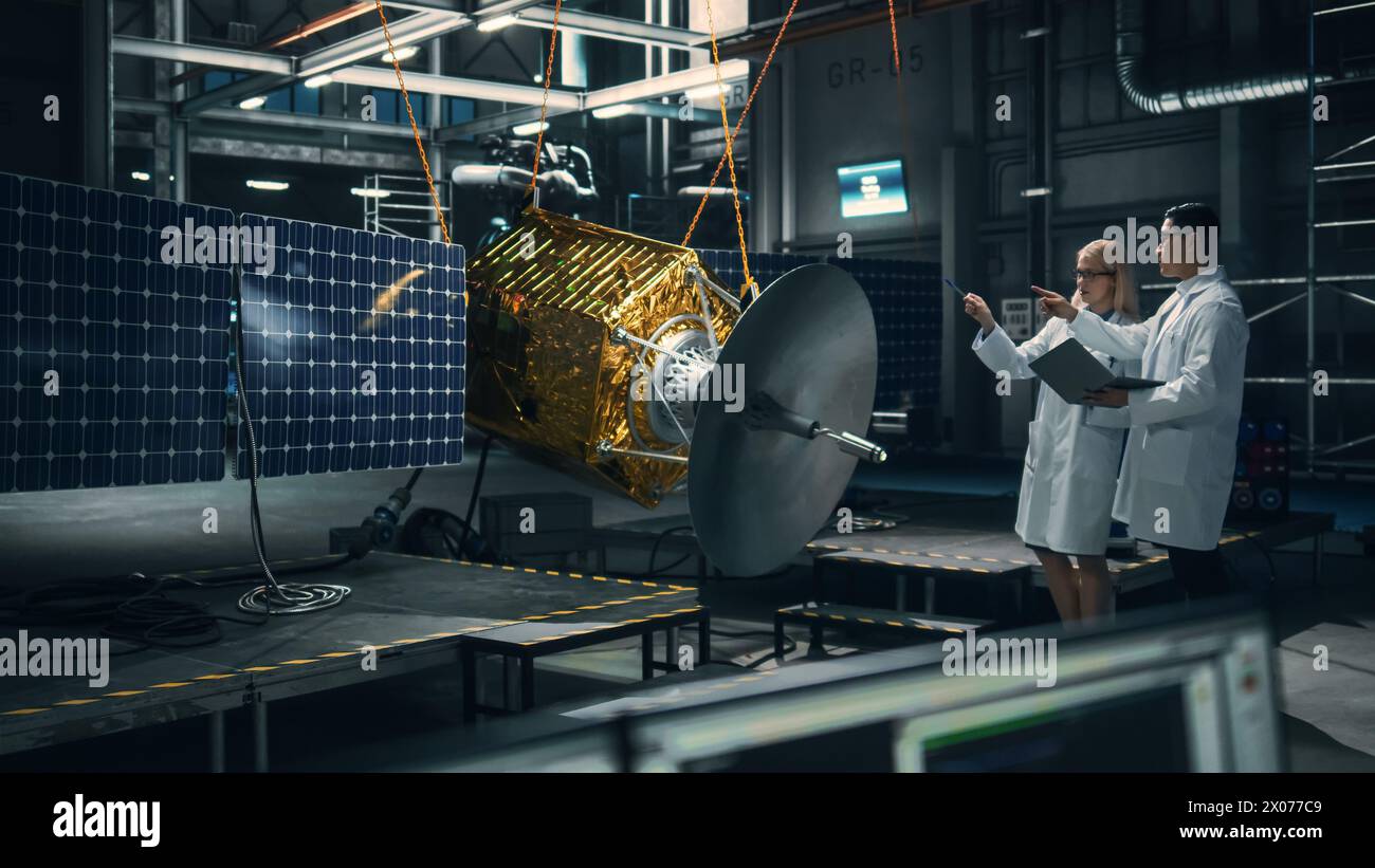 Ingenieur und Techniker, die an der Satellitenkonstruktion arbeiten. Luft- und Raumfahrtbehörde: Ein Team von Wissenschaftlern, das technologische Ausrüstung und Tablet-Computer zur Entwicklung von Raumfahrzeugen für die Weltraumforschung nutzt. Stockfoto