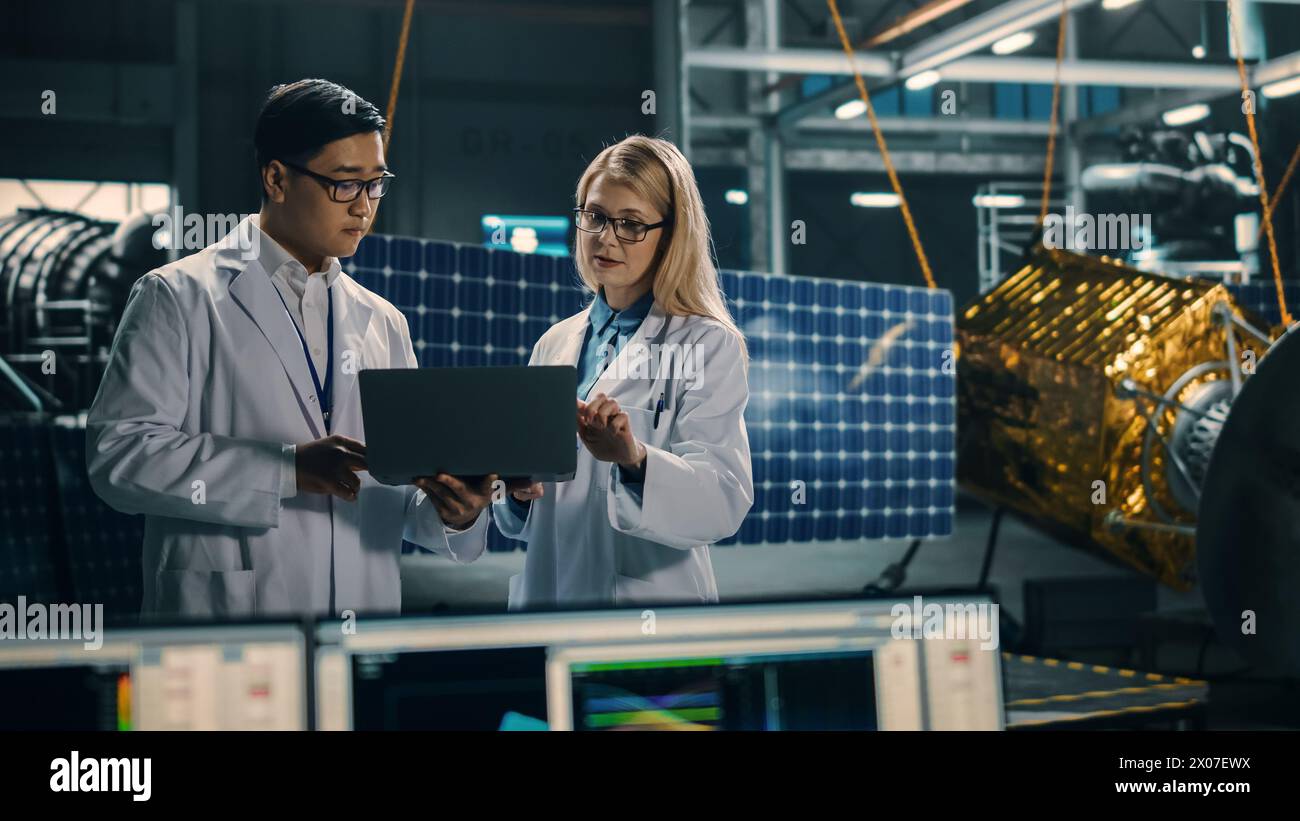 Ingenieur und Techniker, die an der Satellitenkonstruktion arbeiten. Luft- und Raumfahrtbehörde: Ein Team von Wissenschaftlern, die technologische Ausrüstung und Laptop-Computer nutzen, um Raumfahrzeuge für die Weltraumforschung zu entwickeln. Stockfoto