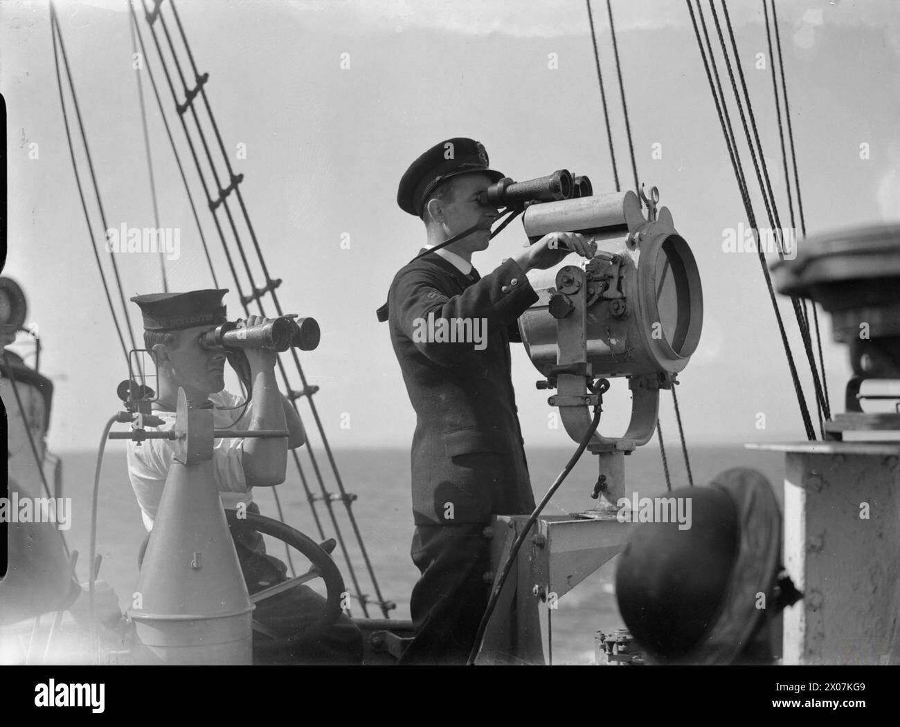 DIE ROYAL NAVY WÄHREND DES ZWEITEN WELTKRIEGS – ein Mitglied der Schiffsbesatzung sendet ein Signal an ein Verfolgungsschiff mit einer Signallampe an Bord der HMS BROKEN, während sie auf See ist Royal Navy BROKEN (HMS) Stockfoto