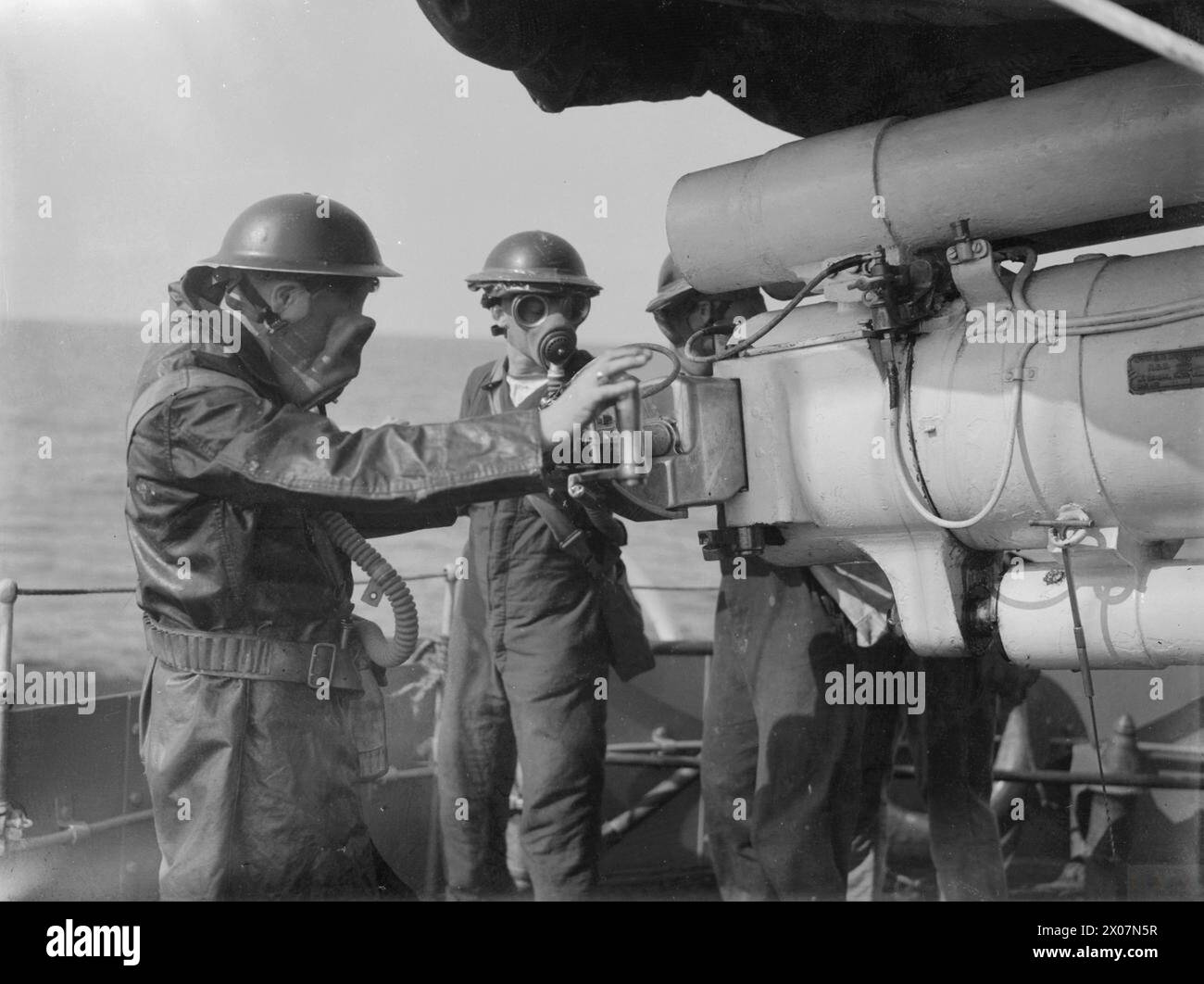 Während des Zweiten Weltkriegs trug eine Besatzung an Bord der HMS Broke Gasmasken an den Einsatzstationen, die auf See die Vorkehrungen für chemische Kriegsführung veranschaulichen. Stockfoto