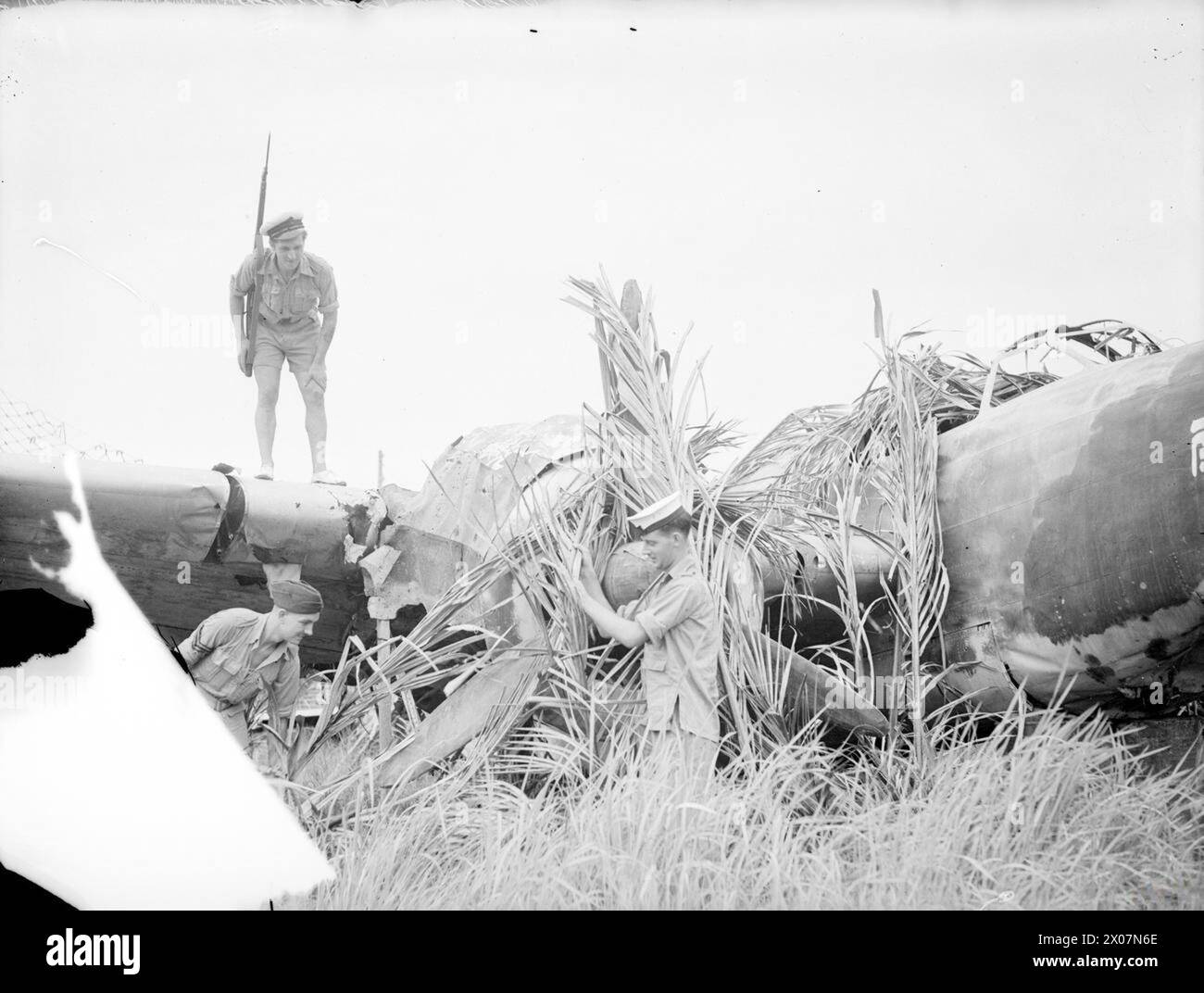 Am 3. September 1945 besetzen die britischen Royal Marines die Siedlung in der Penang-Straße von den japanischen Streitkräften zurück, während Marineflieger zerstörte japanische Flugzeuge inspizieren. Stockfoto