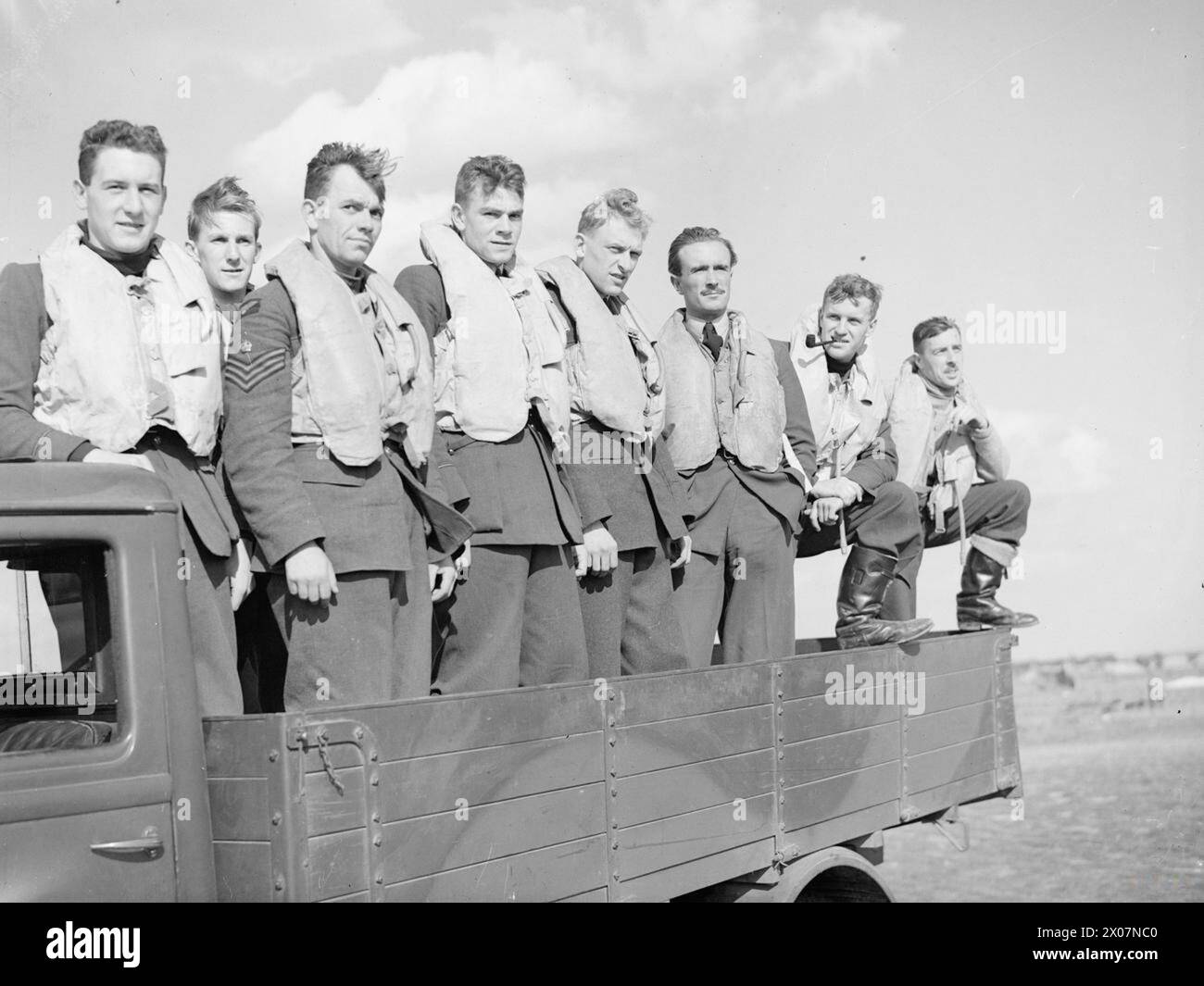 DIE SCHLACHT VON GROSSBRITANNIEN 1940 – Piloten der No. 19 Squadron stehen im Rücksitz eines Lastwagens bei Fowlmere, September 1940. Die Piloten sind von links nach rechts P/O Arthur Vokes, Sgt David Cox, F/Sgt George Unwin, P/O Richard Jones, Sgt Bernard Jennings, P/O Dennis Parrott, unbekannt, unbekannt Stockfoto