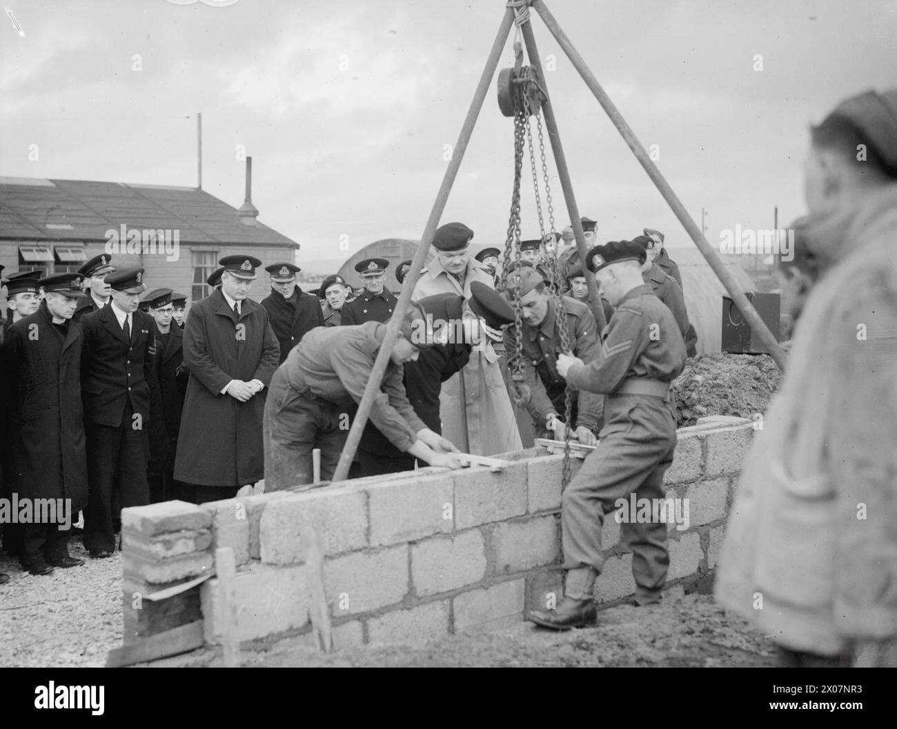 MARINES BAUEN EINEN NEUEN MARINEKLUB. FEBRUAR 1944, FLOTTA. DEN GRUNDSTEIN FÜR EINEN NEUEN MARINEKLUB FÜR DIE FLOTTE LEGTE ADMIRAL P MACNAMARA, CB, CBE, ADMIRAL SUPT DER ORKNEYS. DER CLUB WIRD VON MARINES GEBAUT. - Konteradmiral Macnamara legt den Grundstein für den neuen Club. Hinter ihm, mit gefesselten Händen, ist Captain der Flotte, Captain A C Chapman, CBE, RN Stockfoto