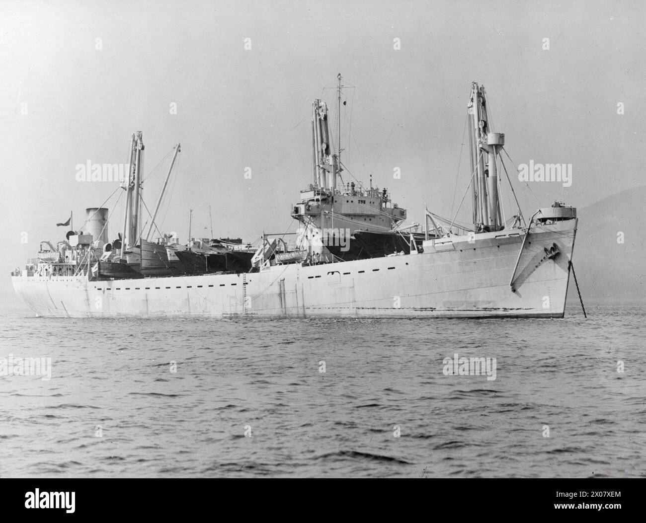 Im November 1944 wurde ein britisches Frachtschiff, das mit drei 120-Tonnen-Derricks ausgerüstet ist, für seine schnelle Schifffahrt dokumentiert. Stockfoto
