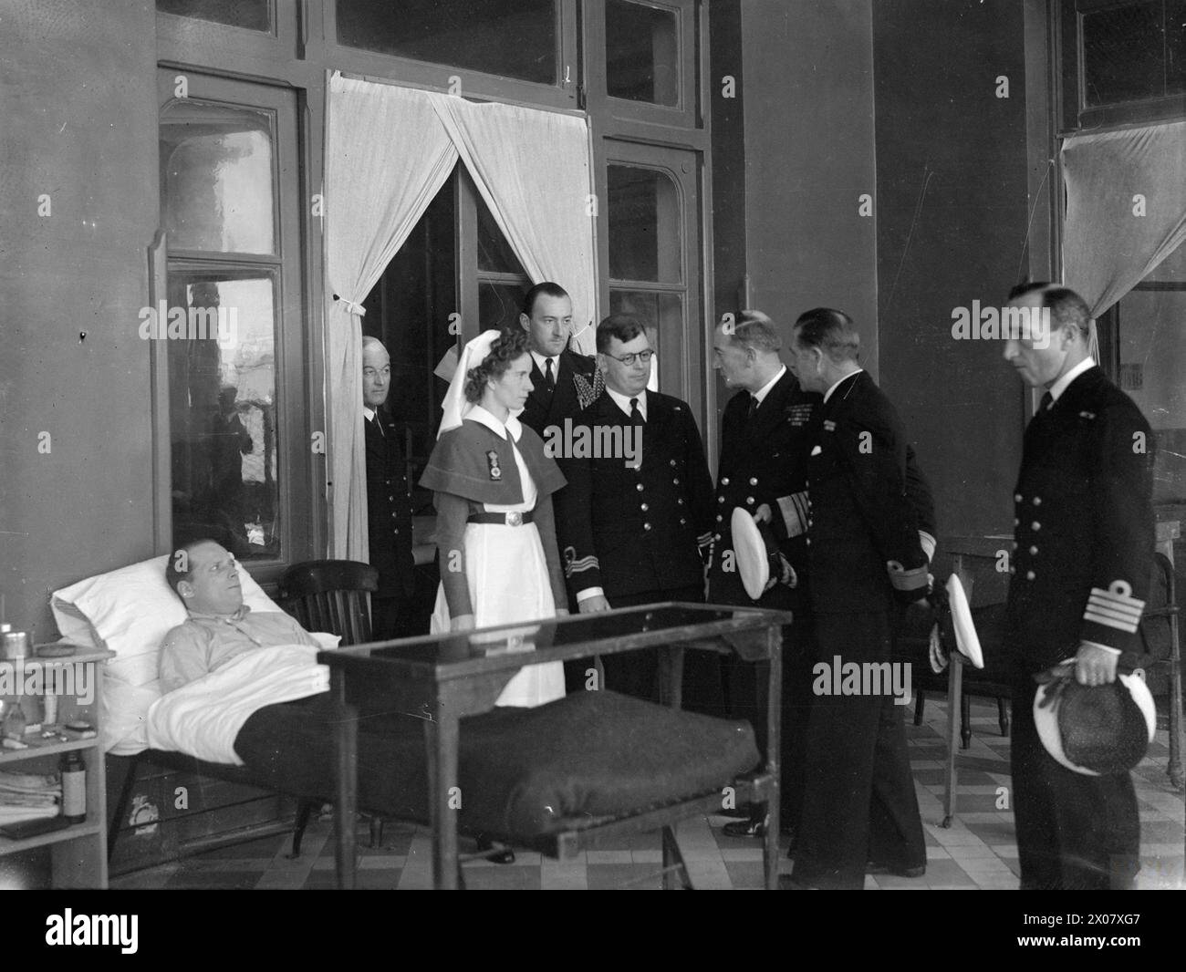 MITTELMEER C IN C BESUCHT MARINEKRANKENHAUS IN ALEXANDRIA. FEBRUAR 1945, ALEXANDRIA. DER BESUCH DES KÖNIGLICHEN MARINESCHIFFSKRANKENHAUSES VON ADMIRAL SIR JOHN CUNNINGHAM, KOMMANDEUR IM OBERSTEN MITTELMEER. - Admiral Cunningham spricht am Bett des leitenden Krankenkrankenhauswärters T A Walton von Kirkcaldy, Schottland, von der HMS SIRIUS Stockfoto