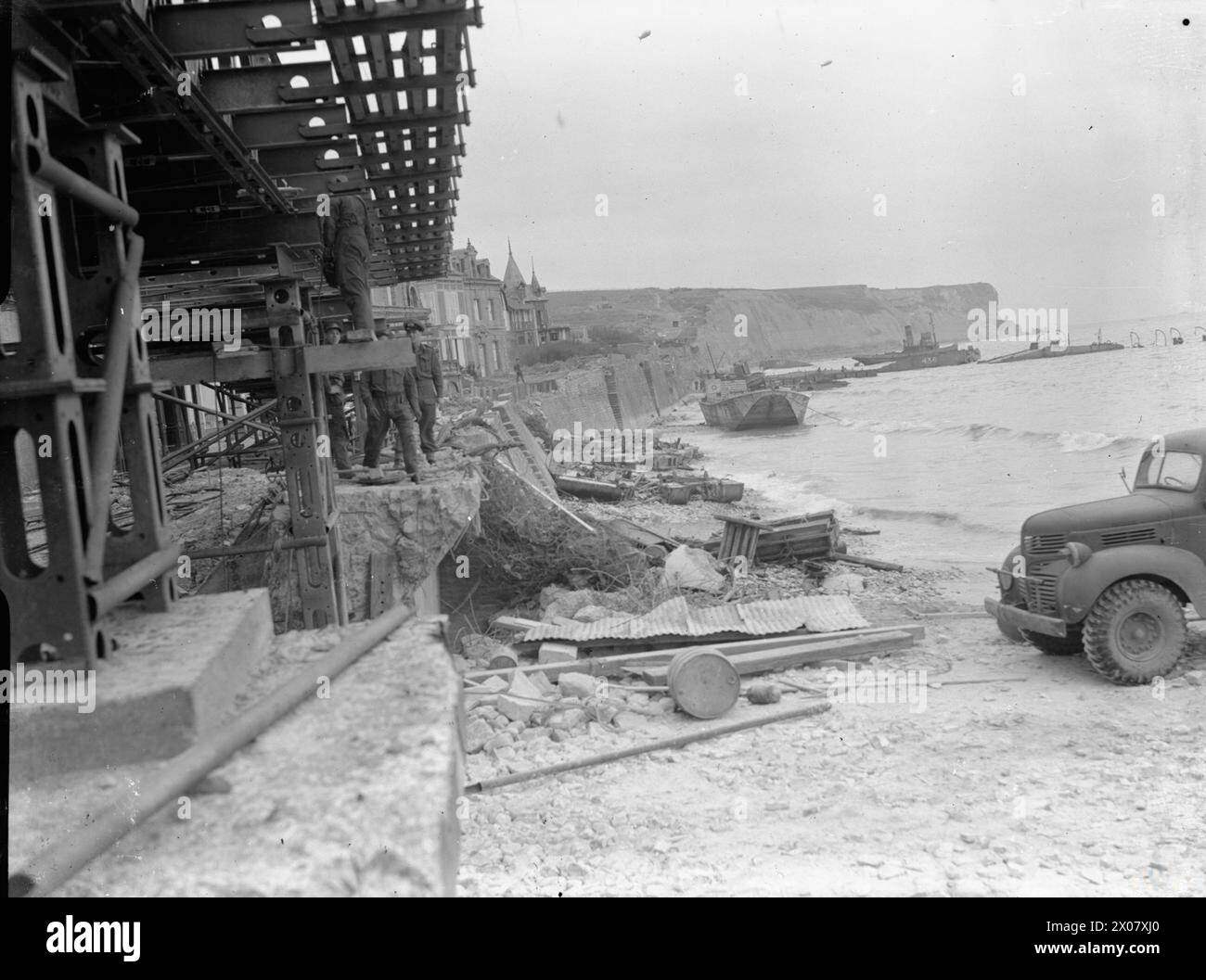 Nach einem schweren Sturm im Juni 1944 liegen während des Normandie Wrackteile aus den Mulberry-Häfen am Strand von Arromanches, was die alliierte Logistik beeinträchtigt. Stockfoto