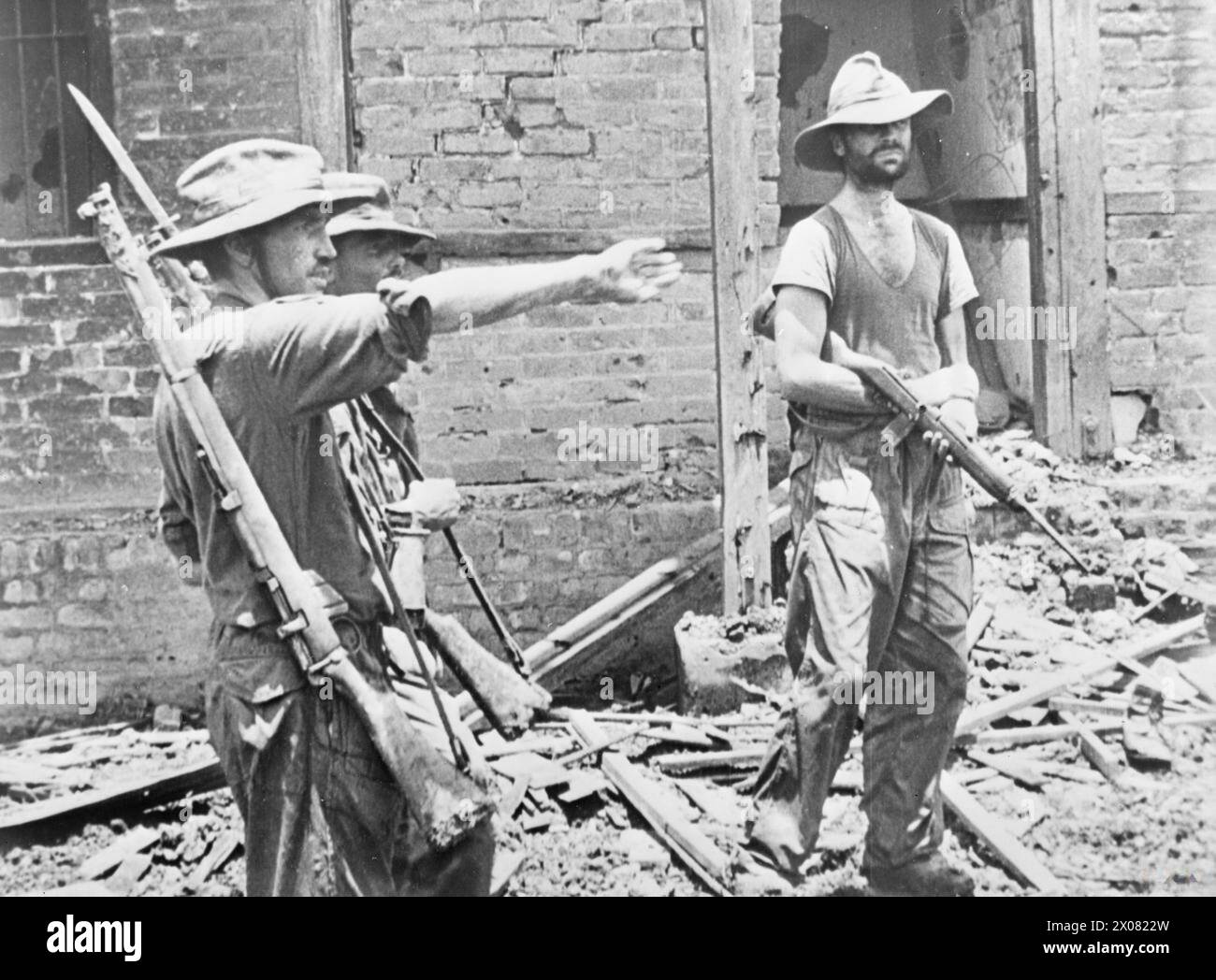 Brigadier Mike Calvert erteilt Lieutenant-Colonel Shaw Befehle, während Major James Lumley nach der Eroberung von Mogaung, Burma, während der zweiten Chindit-Expedition im Juni 1944 einen M1-Karabiner hält. Stockfoto
