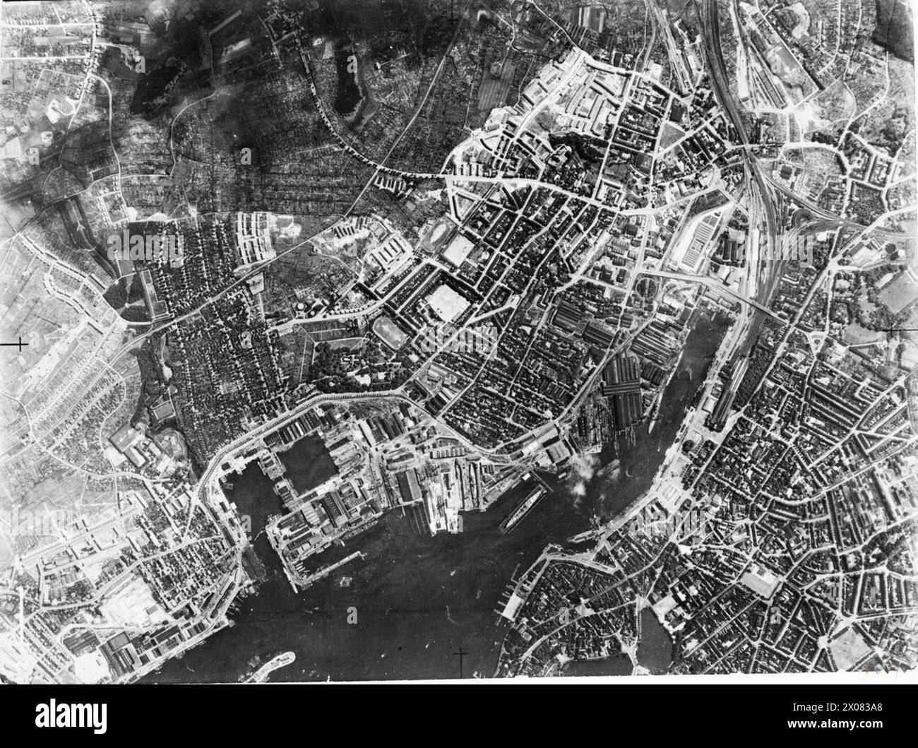 Ein Supermarine Spitfire der RAF Photographic Reconnaissance Unit fliegt über den Kieler Hafen (1939–1945) und erobert den Handelshafen, die Germania Werften von Krupp, die Süd- und Kaiserlichen Werften, das Schlachtschiff Scharnhorst, das Marine Arsenal und die Deutsche Werke A G Werften. Stockfoto