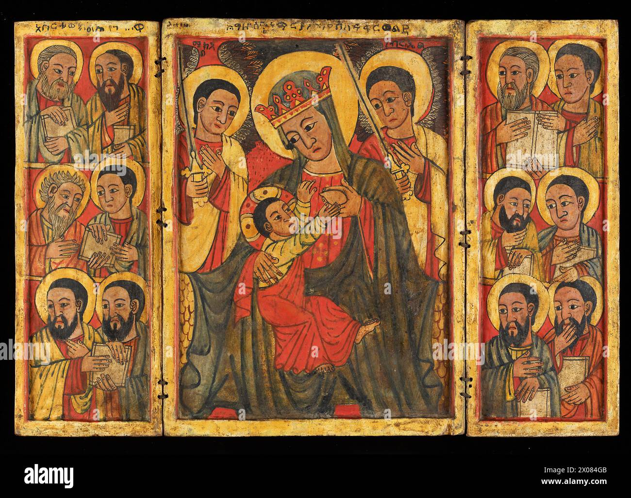 Icon - Äthiopisch-Orthodox - diese äthiopisch-orthodoxe Ikone ist von der Kunst der europäischen Renaissance beeinflusst und zeigt die Jungfrau Maria, die den Säugling Christus pflegt, auf der Mitteltafel. Die Figuren der zwölf Apostel sind in den gegenüberliegenden Seitentafeln dargestellt, die das Triptychon auf die Mitte oder zweite Hälfte des 15. Jahrhunderts datieren. Stockfoto