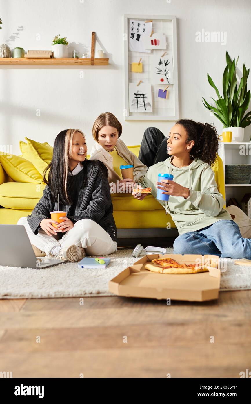 Multikulturelle Teenager-Freunde sitzen zusammen auf einem leuchtend gelben Sofa, wo sie sich in gemütlicher Atmosphäre lachen und miteinander verbinden. Stockfoto