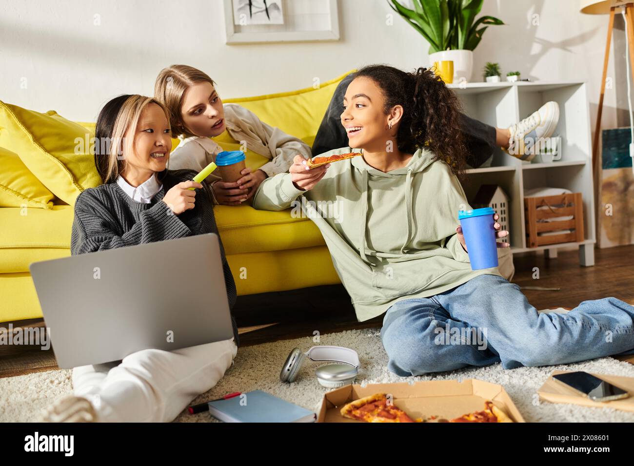Eine Gruppe von Mädchen im Teenageralter genießt Pizza, während sie auf dem Boden sitzen und sich über Essen und Freundschaft unterhalten. Stockfoto