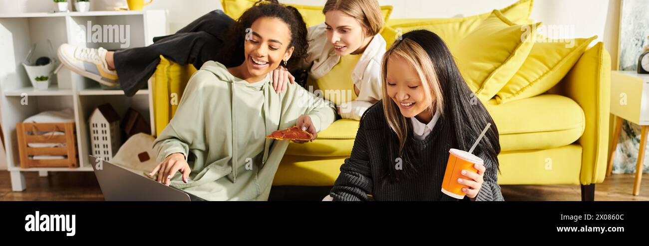 Interrassische Teenager-Mädchen, die Freundschaft auf einer gelben Couch genießen, während sie zu Hause sitzen und sich unterhalten. Stockfoto