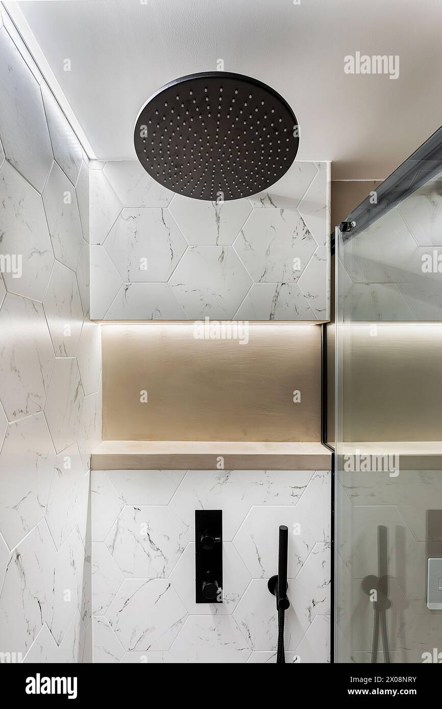 Luxuriöses Marmorbadezimmer mit elegantem Regenduschkopf und moderner Einrichtung Stockfoto