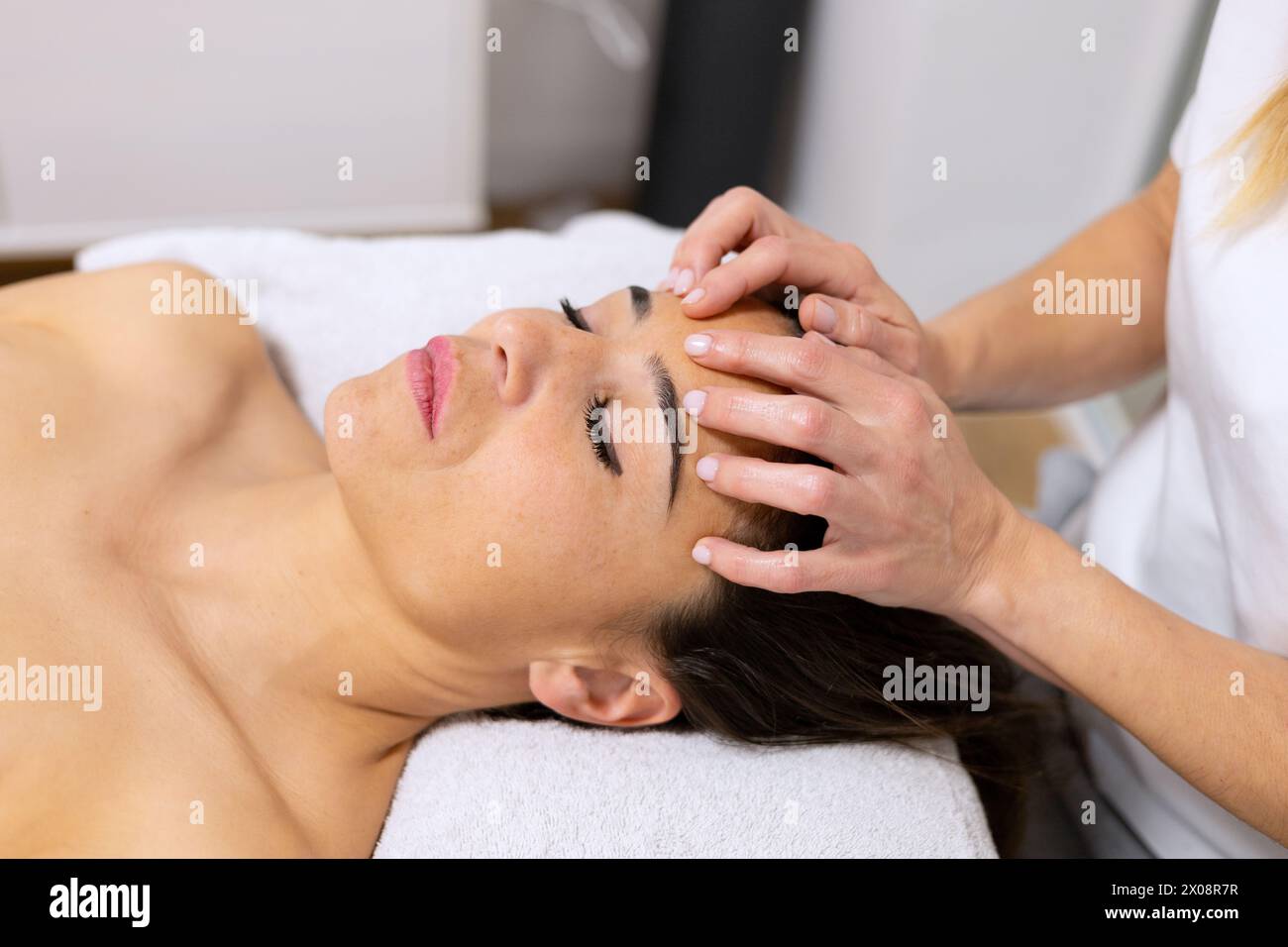 Ein erfahrener Massagetherapeut führt eine sanfte Rückenmassage bei einem entspannten Kunden in einer ruhigen Umgebung durch Stockfoto