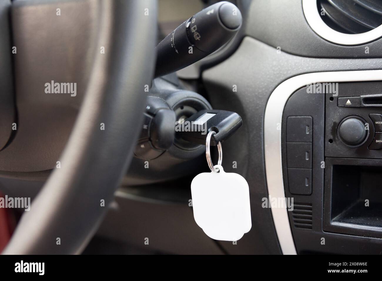 Nahaufnahme der Zündung eines Fahrzeugs mit eingeschaltetem Schlüssel und leerem Schlüsselanhänger, bereit für Branding oder Personalisierung im Fahrzeuginnenraum Stockfoto