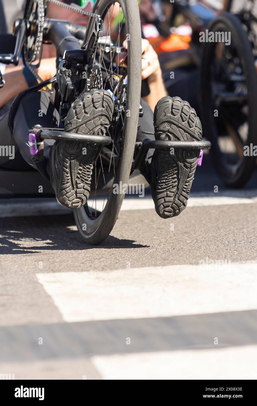 Abgeschnittene, nicht erkennbare Aufnahme einer weiblichen Handradrennerin, die ihre Schuhe mitten im Wettkampf auf den Pedalen präsentiert. Stockfoto