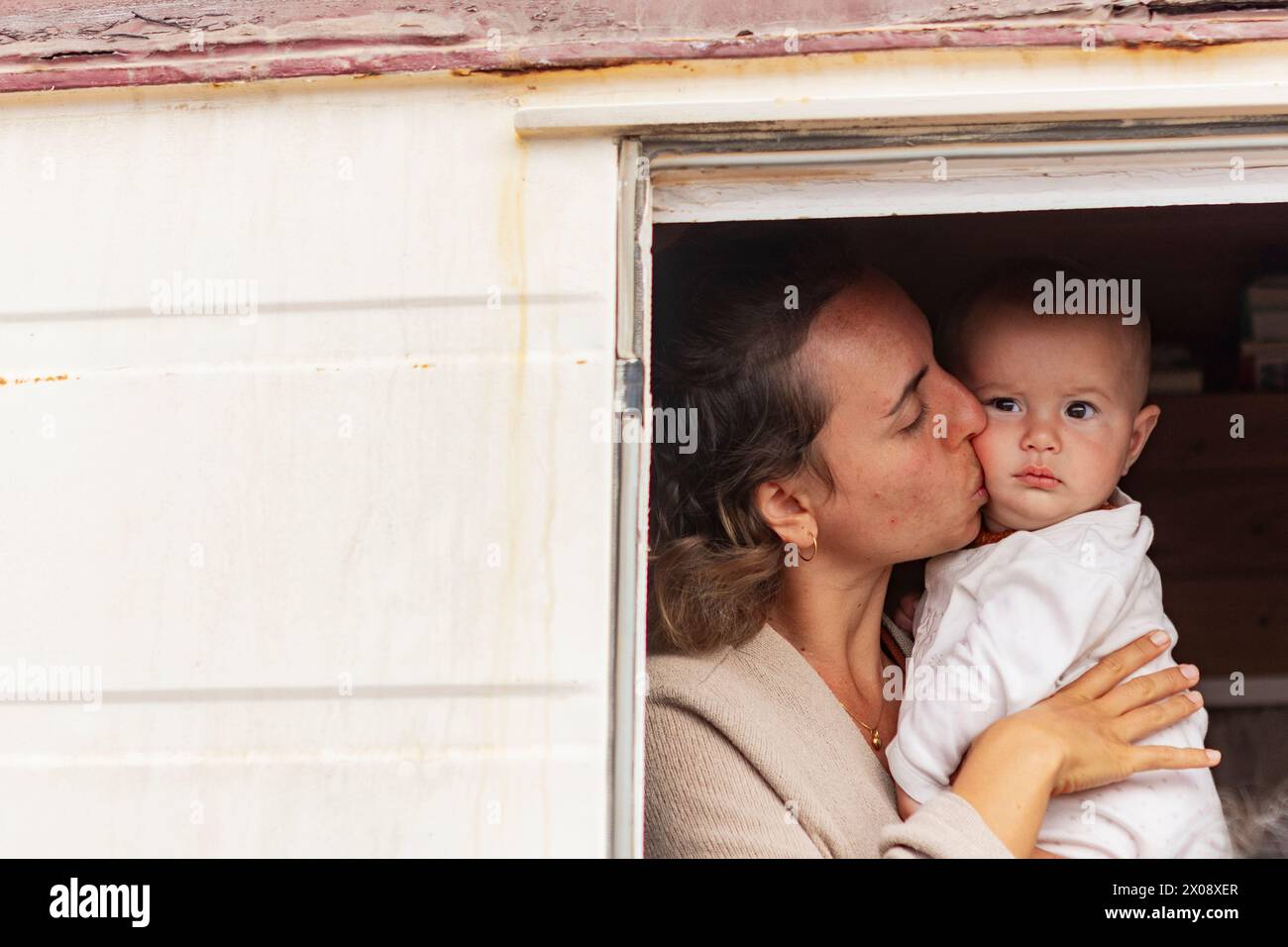 Seitenansicht einer intimen Szene einer Mutter, die ihr Baby am Eingang ihres Hauses auf Rädern schätzt. Stockfoto