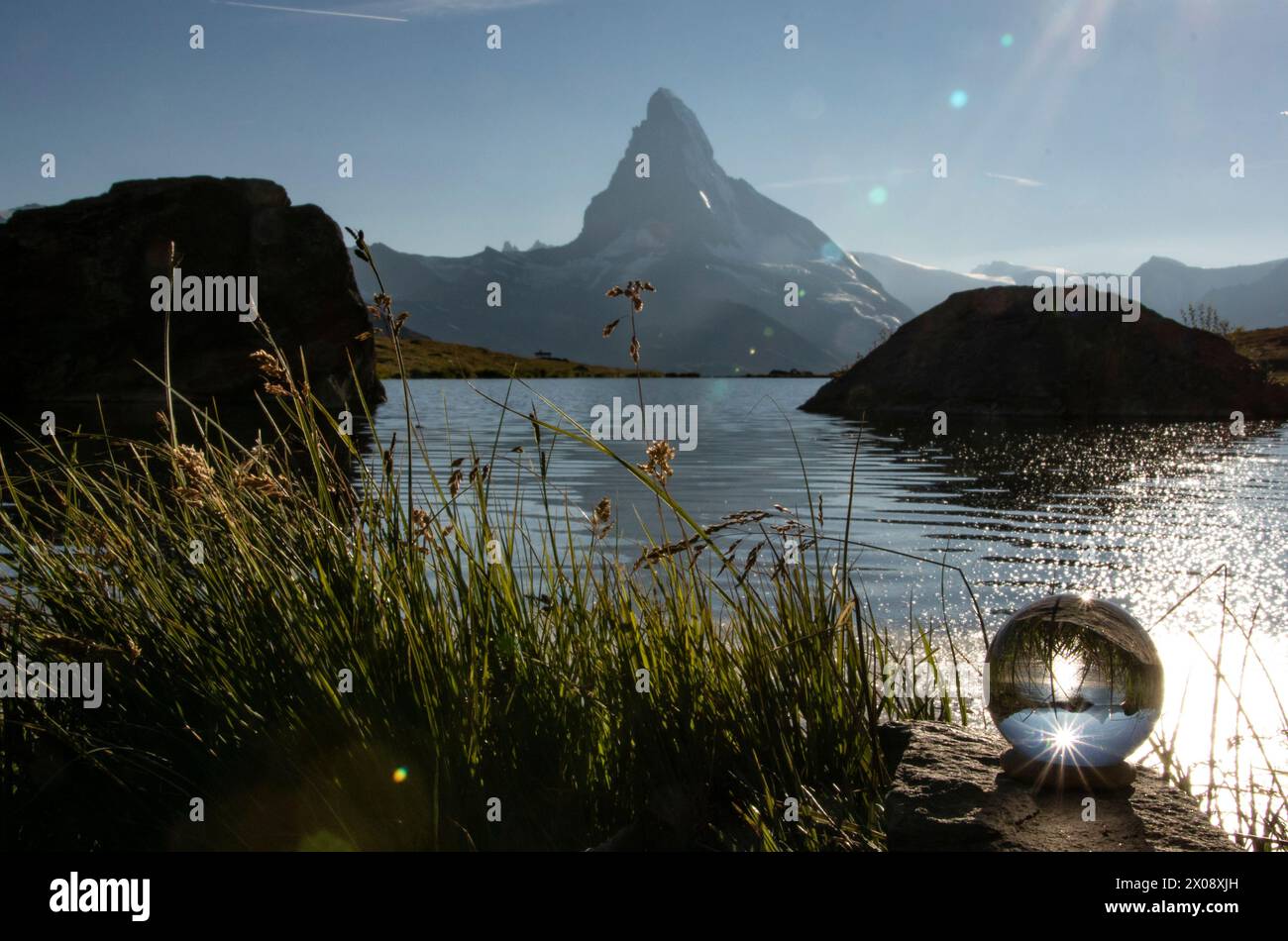 Eine Kristallkugel fängt das glitzernde Wasser des Stellisees und das majestätische Matterhorn in einer einzigartigen Perspektive ein, umgeben von der natürlichen Schönheit o Stockfoto