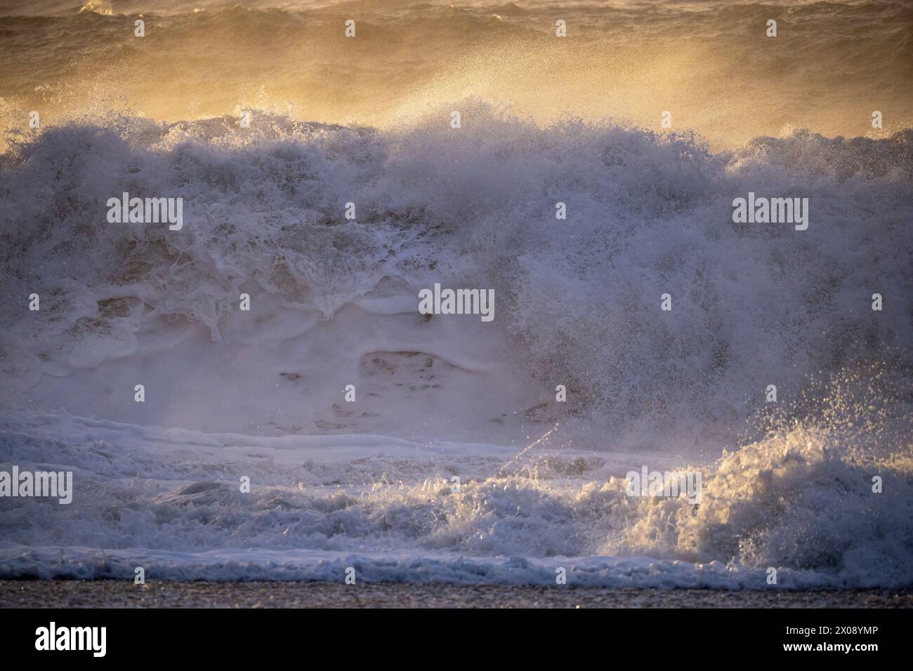 Ein dramatischer Blick auf mächtige Wellen, die während der goldenen Stunde entlang der Küste Islands brechen Stockfoto